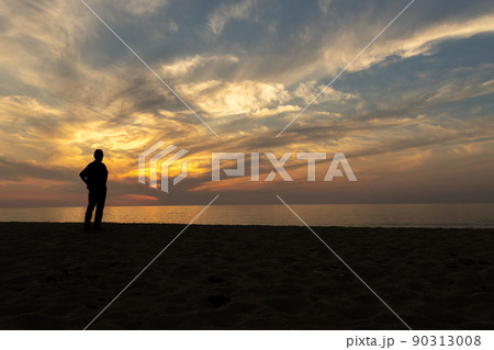 京都府京丹後市の夕日ヶ浦海岸の夕焼けと男性のシルエット 90313008