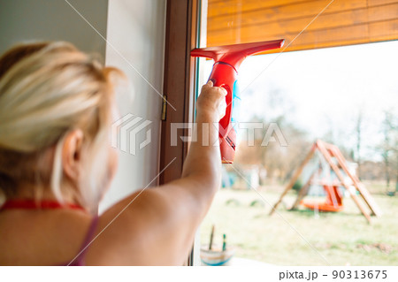 Cleaning windows with portable professional vacuum cleaner. People, housework and housekeeping concept  90313675