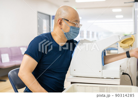 血圧計で血圧測定する男性 90314285