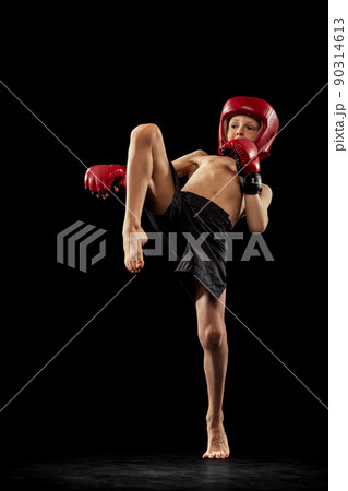 Studio shot of preschool boy, cute kid in sports shots and gloves training alone on black background. Sport, education, action, motion concept. Studio shot of preschool boy, cute kid in sports shots and gloves training alone on black background. Sport, education, action, motion concept. 90314613