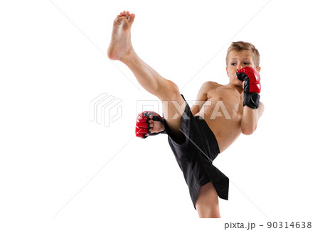 Beginner athlete, kid in sports shots and gloves practicing thai boxing on white studio background. Sport, education, action, motion concept. 90314638