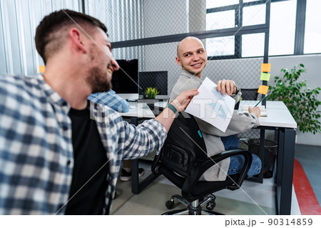 Businessman passing over paper to his colleague in office 90314859