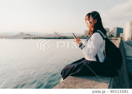 制服姿の女子高生と美しい夕焼け空 90315081