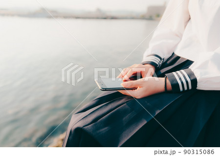 制服姿の女子高生と美しい夕焼け空 90315086