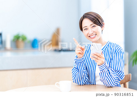 リビングでスマホを操作するミドル女性 90316851