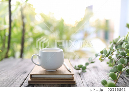 Small cup of coffee and notebooks and plant on wooden table 90316861