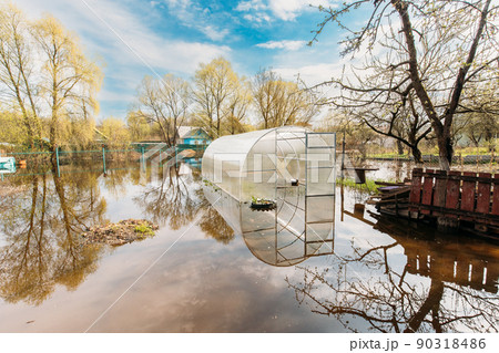 Vegetable Garden Beds In Water During Spring Flood floodwaters during natural disaster. Greenhouse Hothouse in Water deluge During A Spring Flood. inundation River Vegetable Garden Beds In Water During Spring Flood floodwaters during natural disaster. Greenhouse Hothouse in Water deluge During A Spring Flood. inundation River 90318486