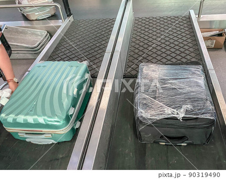 baggage on the tape at the airport. two suitcases are traveling along the line. things are stacked. suitcases packed in a transparent film. the safety of things baggage on the tape at the airport. two suitcases are traveling along the line. things are stacked. suitcases packed in a transparent film. the safety of things 90319490