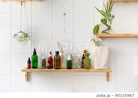 Wooden shelves with cosmetics and toiletries against white tiled wall. Hanging glass pots with green plants. Trendy biophilic and eco friendly minimalistic design Wooden shelves with cosmetics and toiletries against white tiled wall. Hanging glass pots with green plants. Trendy biophilic and eco friendly minimalistic design 90320967