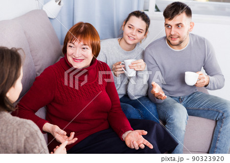 Cheerful family meeting female guest at home 90323920