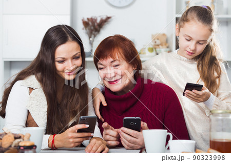Happy grandmother, mother and daughter using mobile gadgets 90323998