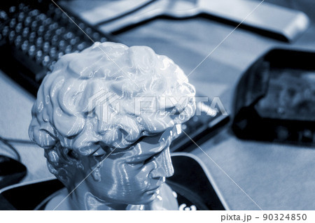Gray human head on 3d printed close-up. An object prototype of a human head with hair printed by a 3D printer stands on a table. New modern additive 3D printing technology. Fused deposition modeling Gray human head on 3d printed close-up. An object prototype of a human head with hair printed by a 3D printer stands on a table. New modern additive 3D printing technology. Fused deposition modeling 90324850