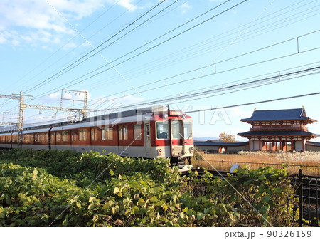 世界遺産の平城宮跡に復元された朱雀門を横目に通過する近鉄電車 90326159