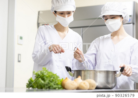白衣を着て食事を作る女性 90326579