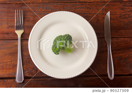 Concept of calorie restriction. Strict diet. Sliced pod isolated on white plate with fork and knife Concept of calorie restriction. Strict diet. Sliced pod isolated on white plate with fork and knife 90327309