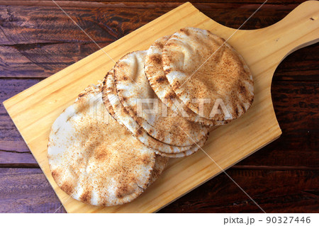 Pita bread isolated on wooden spatula coming out of the oven. Traditional food of Arabic cuisine Pita bread isolated on wooden spatula coming out of the oven. Traditional food of Arabic cuisine 90327446