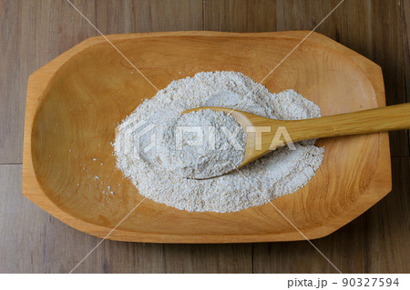 portion of raw whole wheat flour, wooden bowl, wooden table top view 90327594