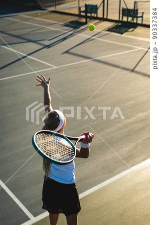 High angle view of young female caucasian tennis player serving during game at court 90337384