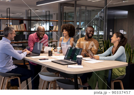 Smiling multiracial colleagues discussing during meeting at modern workplace Smiling multiracial colleagues discussing during meeting at modern workplace 90337457