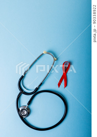 Directly above shot of red aids awareness ribbon and stethoscope against blue background, copy space 90338922