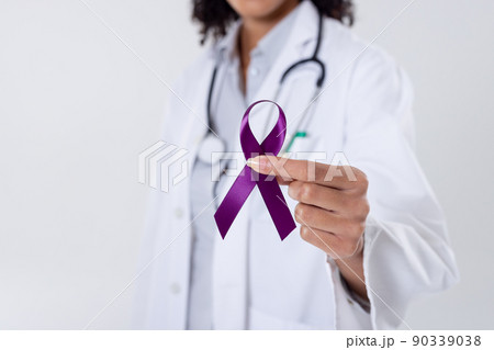 Midsection of african american mid adult female doctor holding purple cancer awareness ribbon Midsection of african american mid adult female doctor holding purple cancer awareness ribbon 90339038
