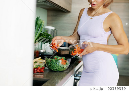 The girl adds carrots to lettuce leaves while cooking dinner. The concept of healthy eating and healthy lifestyle. Diet, detox, vegetarian food The girl adds carrots to lettuce leaves while cooking dinner. The concept of healthy eating and healthy lifestyle. Diet, detox, vegetarian food 90339359