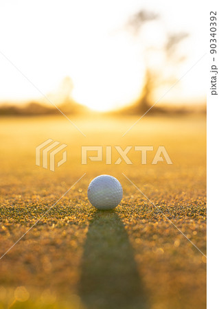 Close-up of golf ball on grassy landscape against clear sky during sunset, copy space 90340392