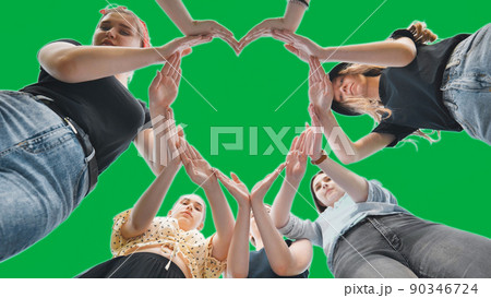 Girlfriends girls make a heart shape from their hands on a green background. 90346724