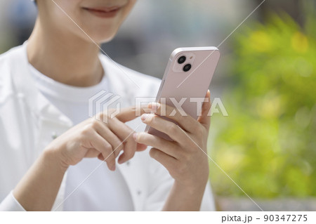 スマートフォンを操作する若い女性の手元 90347275