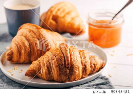 Plate with fresh croissants, jam and coffee on white wooden table. Close up. 90348481