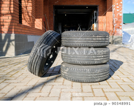 A new set of summer tires stacked on the sidewalk in the yard. A new set of summer tires stacked on the sidewalk in the yard. 90348991