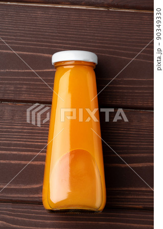 Glass bottle of orange juice on wooden table, top view Glass bottle of orange juice on wooden table, top view 90349330