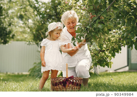 Grandmother and granddaughter together, hugging and joyfully laughing in a Flowering apricot garden in April. Family outdoors lifestyle. 90349984