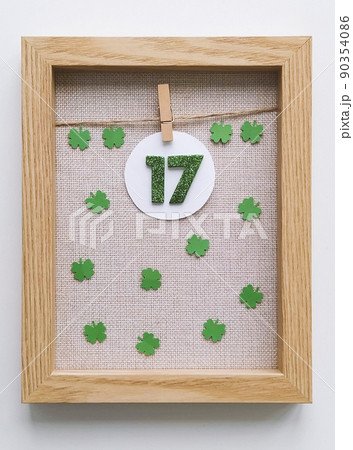 Wooden frame with miniature green numbers 17 with four-leaf clover on fabric background Wooden frame with miniature green numbers 17 with four-leaf clover on fabric background 90354086