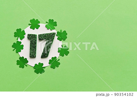 Numeral 17 on white background with frame of paper-cut four-leaf clover leaves 90354102