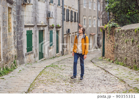 Man tourist on background of Scenic panorama view of the historic town of Risan at famous Bay of Kotor on a beautiful sunny day with blue sky and clouds in summer, Montenegro, southern Europe Man tourist on background of Scenic panorama view of the historic town of Risan at famous Bay of Kotor on a beautiful sunny day with blue sky and clouds in summer, Montenegro, southern Europe 90355331