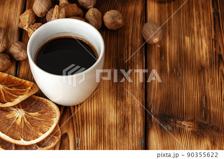 Cup of coffee with nutmeg and dried orange on brown wooden table 90355622