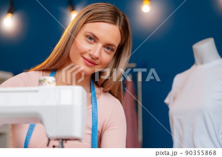Young seamstress working on her sewing machine on textile factory 90355868