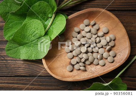 Burdock extract pills and leaves of arctium lappa - latin name for Burdock. Top view. Burdock extract pills and leaves of arctium lappa - latin name for Burdock. Top view. 90356081