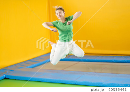 Young woman jumping and bouncing on a trampoline in sport center Young woman jumping and bouncing on a trampoline in sport center 90356441