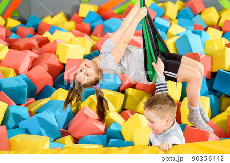 Children playing with soft cubes in the dry pool in play center. playground with foam blocks in trampoline club 90356442
