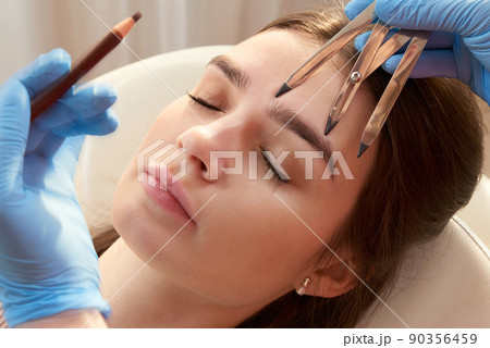 Cosmetologist measures the proportions of the eyebrows with the ruler. 90356459