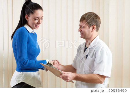 Doctor shaking hand of a female patient and congratulating her with good medical test results Doctor shaking hand of a female patient and congratulating her with good medical test results 90356490