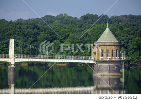5月の狭山丘陵にある狭山湖堰堤から見る取水塔と反射する湖面 90356512