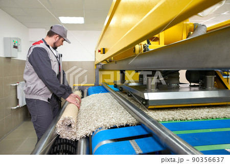 Laundry worker in the process of working on automatic machine for carpet washing in dry cleaning 90356637