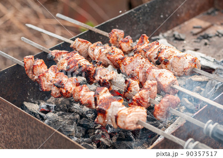 Marinated shashlik preparing on a barbecue grill over charcoal. Shashlik or Shish kebab popular in Eastern Europe Marinated shashlik preparing on a barbecue grill over charcoal. Shashlik or Shish kebab popular in Eastern Europe 90357517