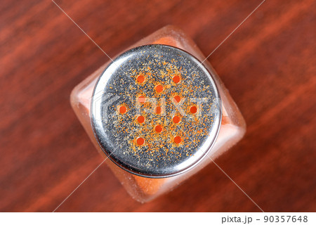 Close-up of the lid of a glass jar with red chilli powder. 90357648