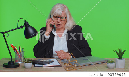 Angry senior old business woman making phone call at office work annoyed boss talking mobile quarrel Angry senior old business woman making phone call at office work annoyed boss talking mobile quarrel 90359095