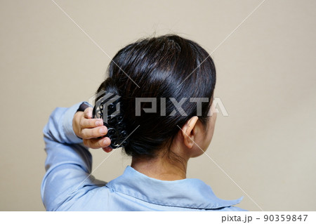 無造作に髪を束ねた中年女性の後ろ姿 90359847