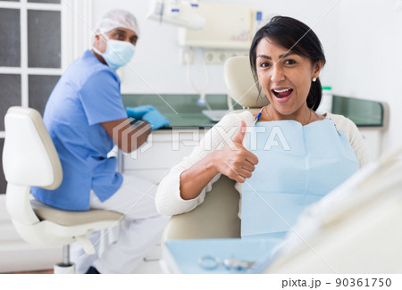 Portrait of satisfied woman visiting dentist giving thumbs up in dental clinic 90361750
